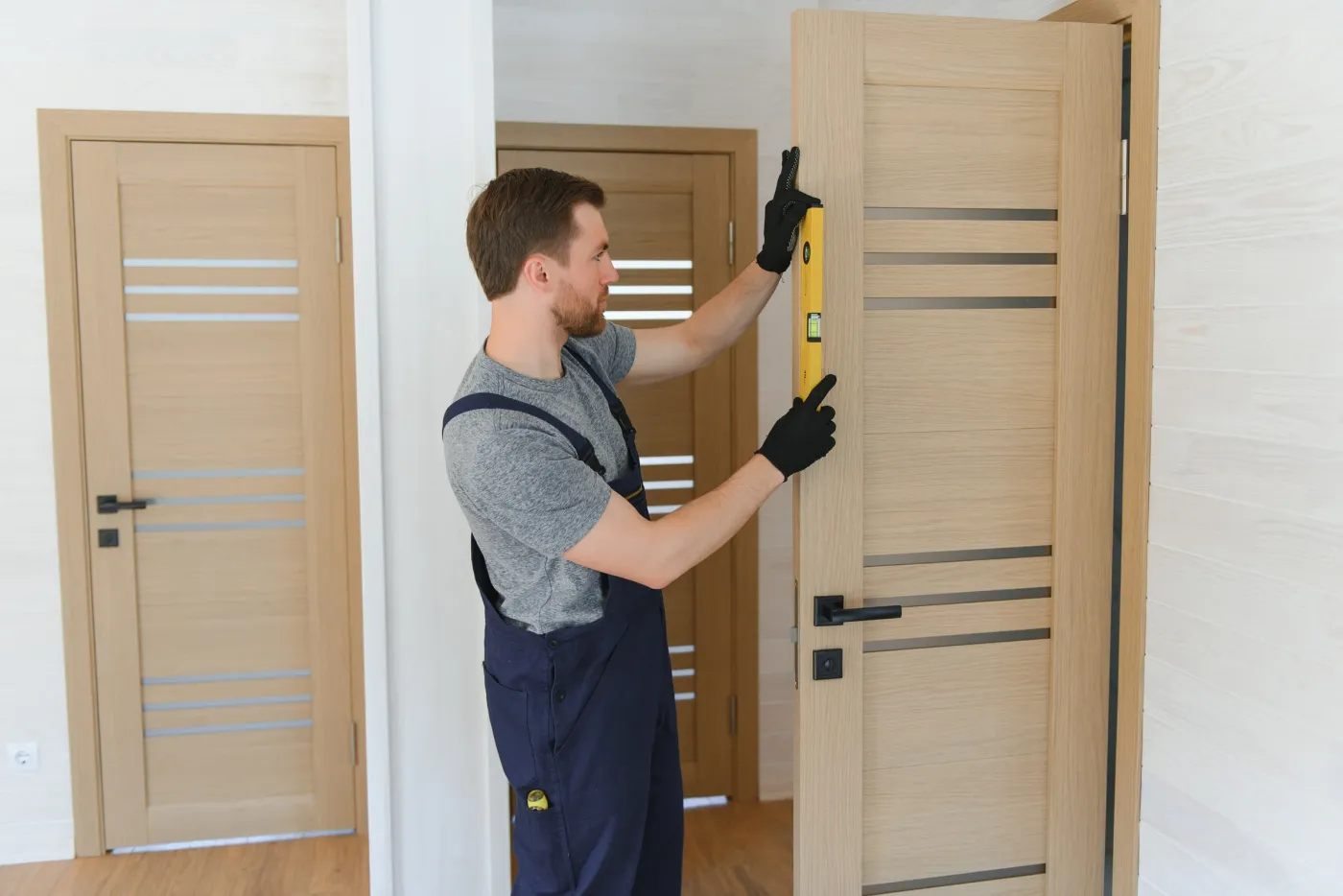 Artisan serrurier ajustant et vérifiant l'aplomb d'une porte d'appartement à Asnières-sur-Seine (92600)